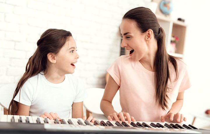mum girl playing piano together